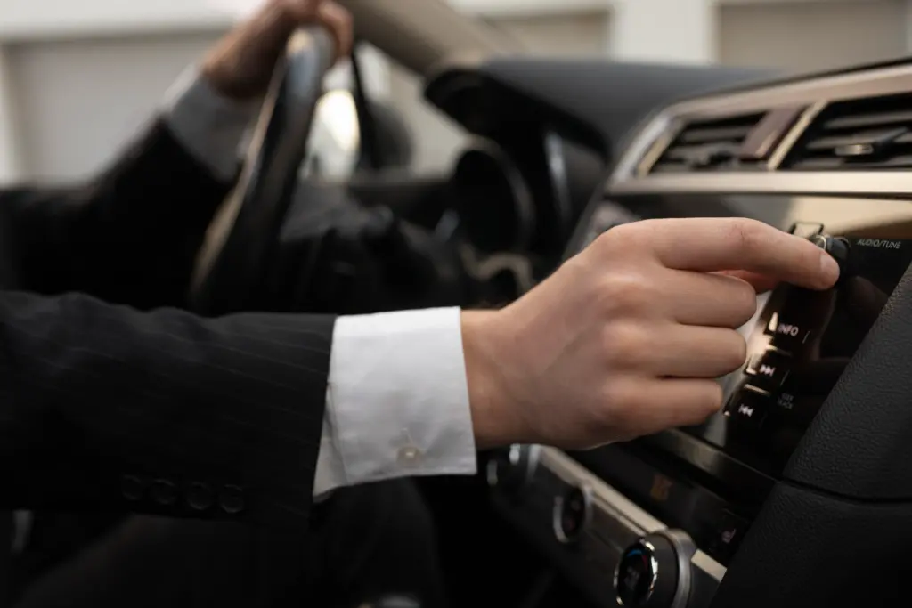 man-using-his-car-s-options-while-driving - Limo company Houston