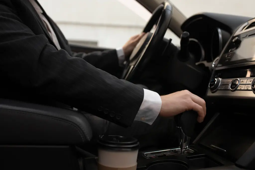 man-using-his-car-s-options-while-driving - Limo company Houston